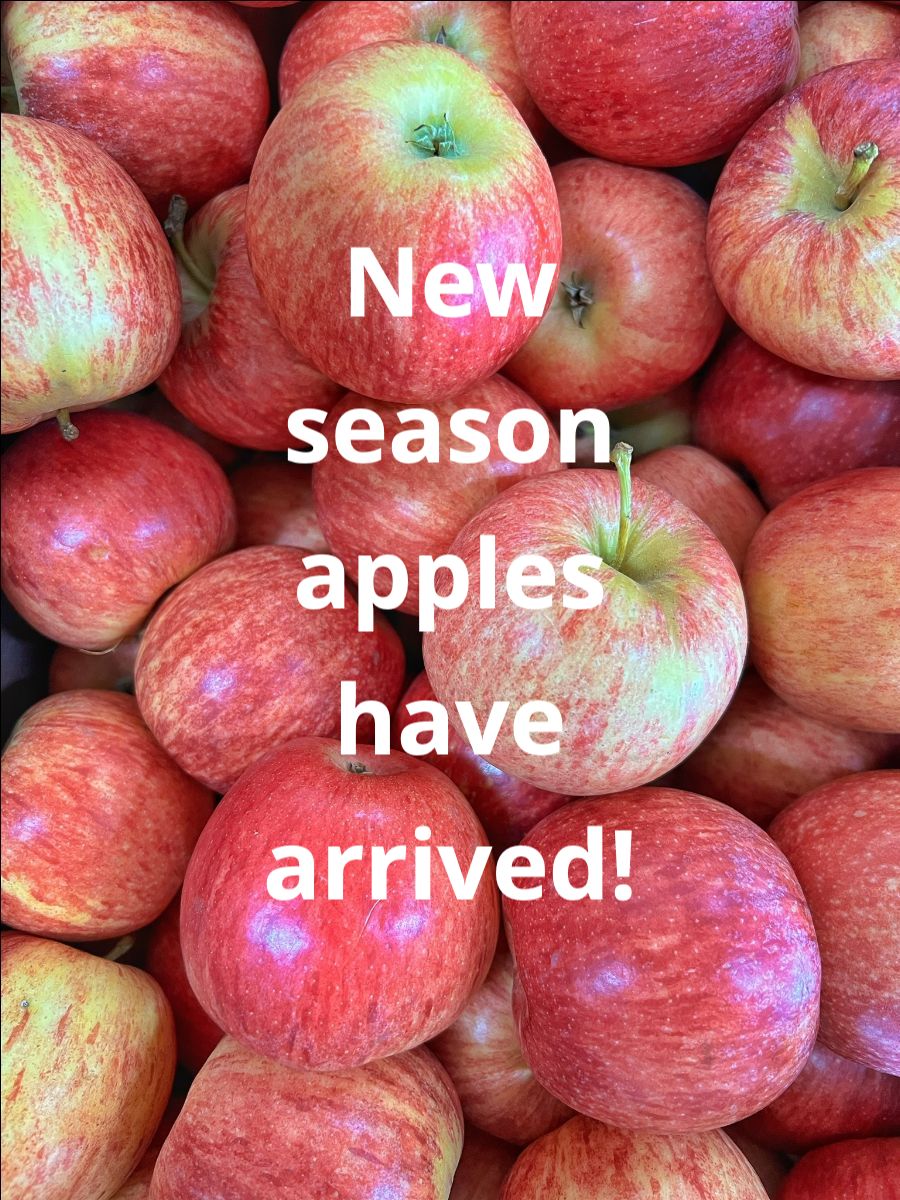 Close-up of a pile of red-and-yellow apples filling the frame. White text over the apples reads, “New season apples have arrived!”