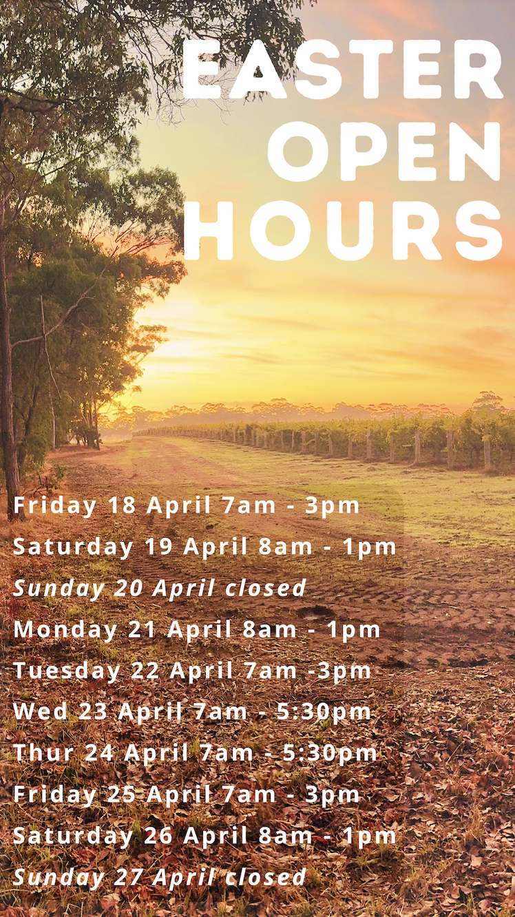 Sunrise over a rural dirt track beside rows of crops and tall trees, with large text reading “EASTER OPEN HOURS.” Smaller text lists opening times for April 18–27, including Fridays 7am–3pm, Saturdays 8am–1pm, and Sundays closed.